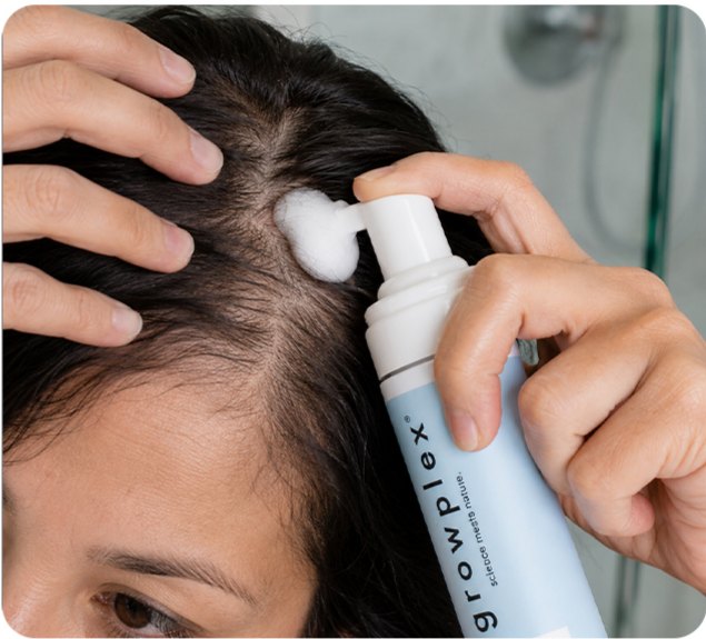 A woman applying Vitafoam to her part line